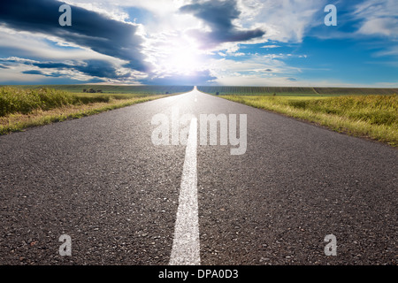 Driving on an empty road to the sun Stock Photo