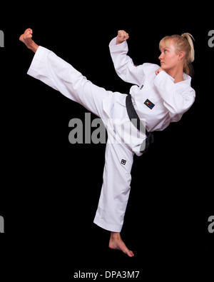 Aggressive young woman in Taekwondo uniform thrusting her fist forward ...