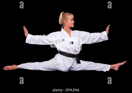 Calm young woman in Taekwondo uniform doing the splits Stock Photo