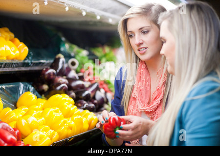 Young women looking at peppers in supermarket Stock Photo