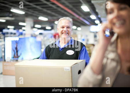 Woman leaving showroom with salesman carrying purchase Stock Photo