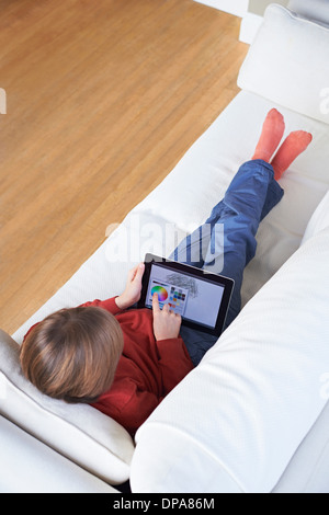 Boy on sofa using digital tablet Stock Photo