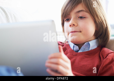 Boy on sofa using digital tablet Stock Photo