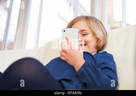 Girl on sofa using smartphone Stock Photo