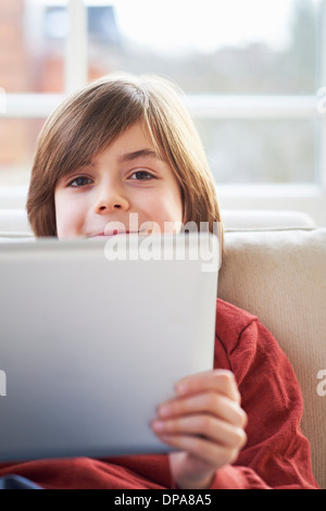 Boy on sofa using digital tablet Stock Photo