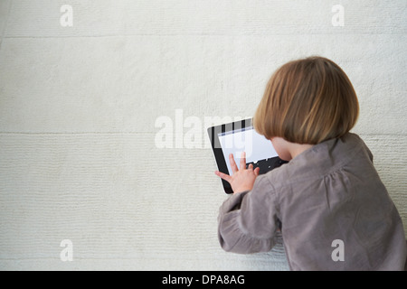 Girl lying on floor using digital tablet Stock Photo