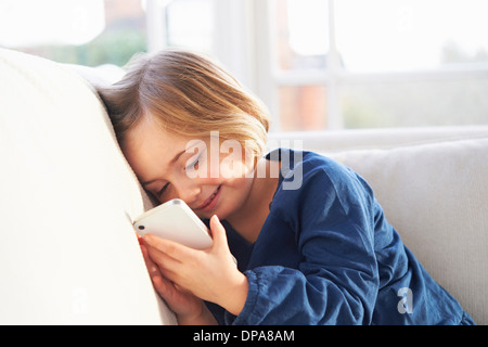 Girl on sofa using smartphone Stock Photo