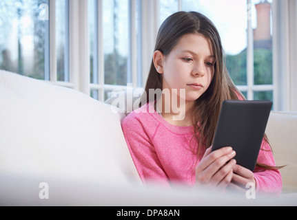 Girl using digital tablet on sofa Stock Photo