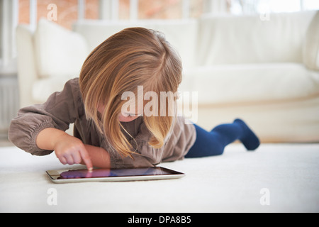 Girl lying on floor using digital tablet Stock Photo