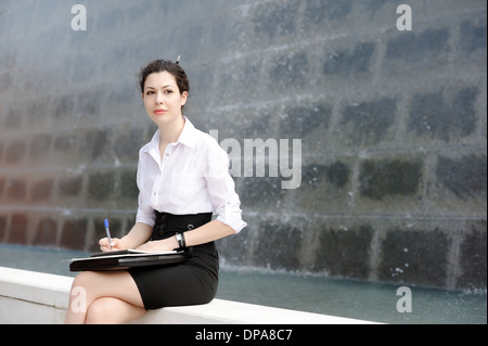 Young office worker sitting on bench with files Stock Photo