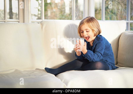 Girl on sofa using smartphone Stock Photo