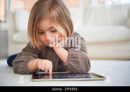 Girl lying on floor using digital tablet Stock Photo