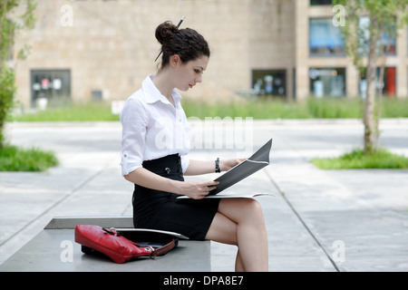 Office worker reading paperwork on bench Stock Photo