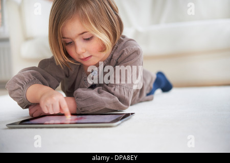 Girl lying on floor using digital tablet Stock Photo