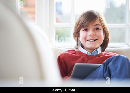 Boy on sofa using digital tablet Stock Photo