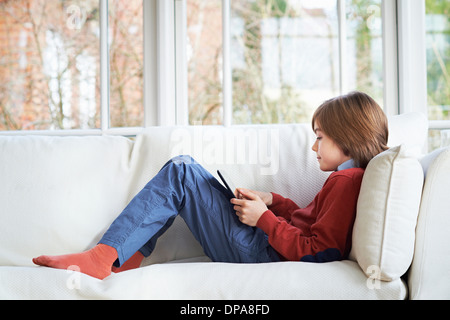 Boy on sofa using digital tablet Stock Photo