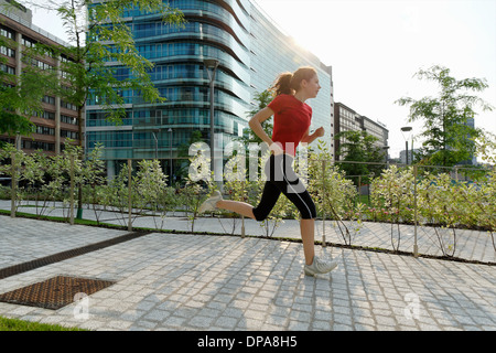 Young woman running past office buildings Stock Photo