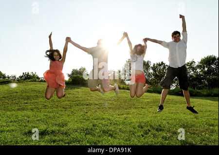 Group of young adults jumping mid air in field Stock Photo