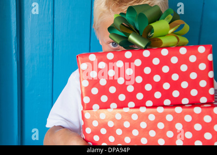 Boy peeping behind gifts in hand Stock Photo