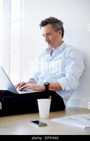 Man sitting on floor sing laptop Stock Photo