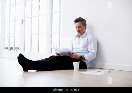 Man sitting on floor looking at paperwork Stock Photo