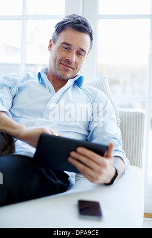 Man sitting on sofa using digital tablet Stock Photo