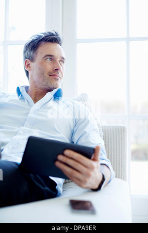 Man sitting on sofa using digital tablet Stock Photo