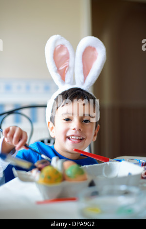 Boy wearing bunny ears painting Easter eggs Stock Photo