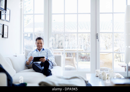 Man relaxing on sofa using digital tablet Stock Photo
