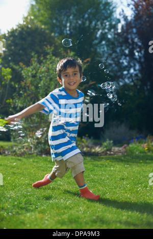 Boy playing with bubbles in garden Stock Photo