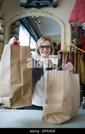Young caucasian woman holding shopping bags at retail shop surprised ...