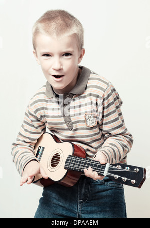 Portrait of boy (7 years) playing guitar. Stock Photo