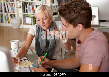Two colleagues talking, woman making notes Stock Photo