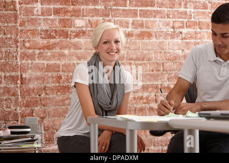 Two colleagues at desk, man making notes Stock Photo