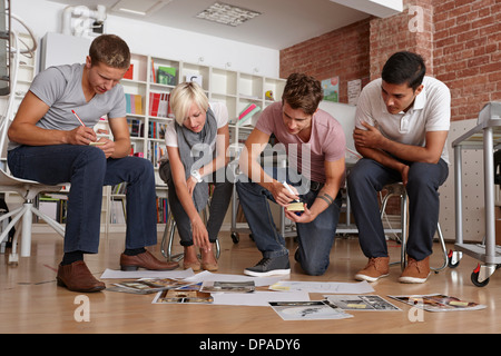 Colleagues in meeting looking at papers on floor Stock Photo