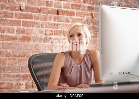 Portrait of mid adult woman at desk with brick wall Stock Photo