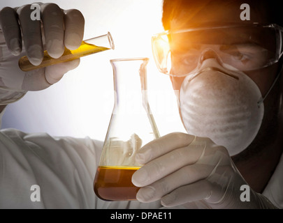 Close up of scientist pouring liquid into flask Stock Photo