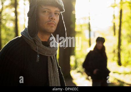 Portrait of mid adult man wearing hat and scarf, woman in background Stock Photo