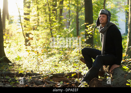 Portrait of mid adult man sitting on log in forest