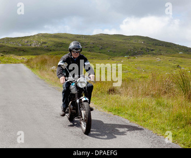 Senior male motorcyclist riding on rural road Stock Photo