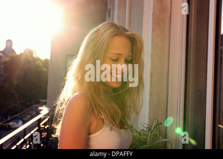 Young woman standing on city apartment balcony Stock Photo