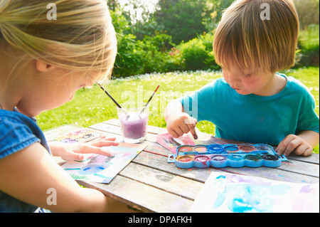 Brother and sister finger painting in garden Stock Photo