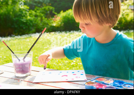 Young boy finger painting in garden Stock Photo