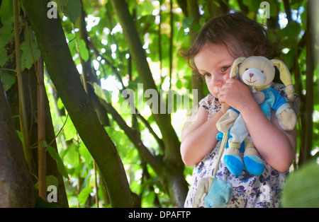 Portrait of female toddler with cuddly toy in woods Stock Photo