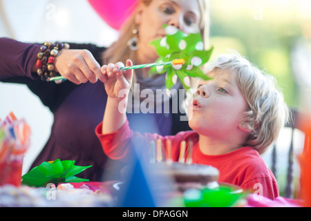 Young boy blowing windmill at birthday party Stock Photo