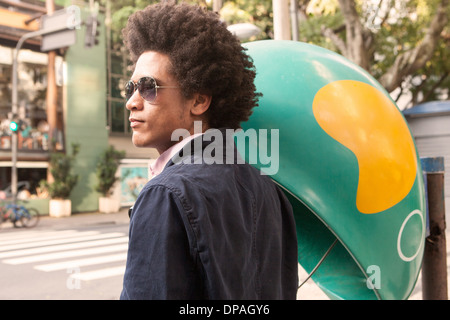 Young man in sunglasses by pay telephone