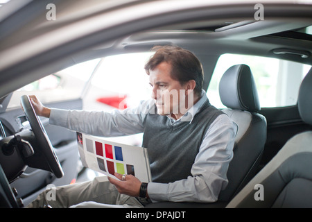 Mid adult man checking dashboard in car showroom Stock Photo