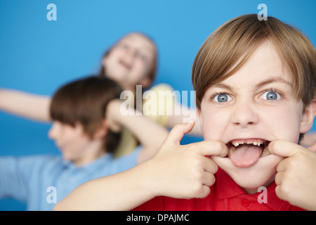 Portrait of boy sticking out tongue, blue background Stock Photo