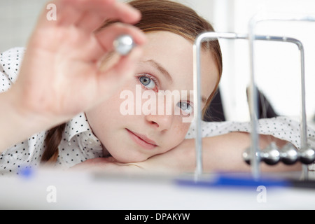 Girl playing with newton's cradle on desk Stock Photo