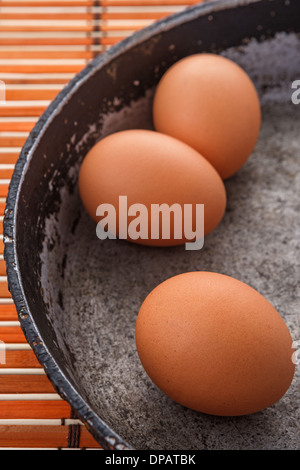 three brown eggs on an old pan Stock Photo
